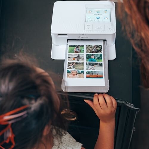 Children watching photos being printed on a printer.