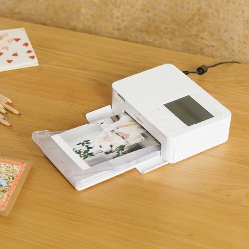 Compact photo printer printing a picture on a wooden desk.