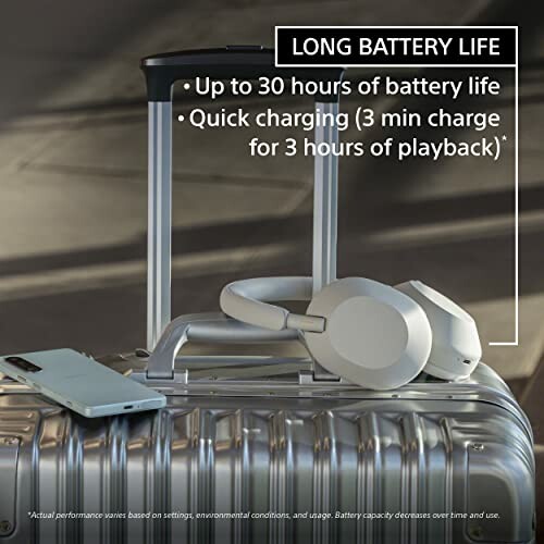 Headphones and smartphone on suitcase, highlighting long battery life and quick charging.