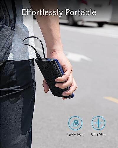 Person holding a portable power bank on a street.